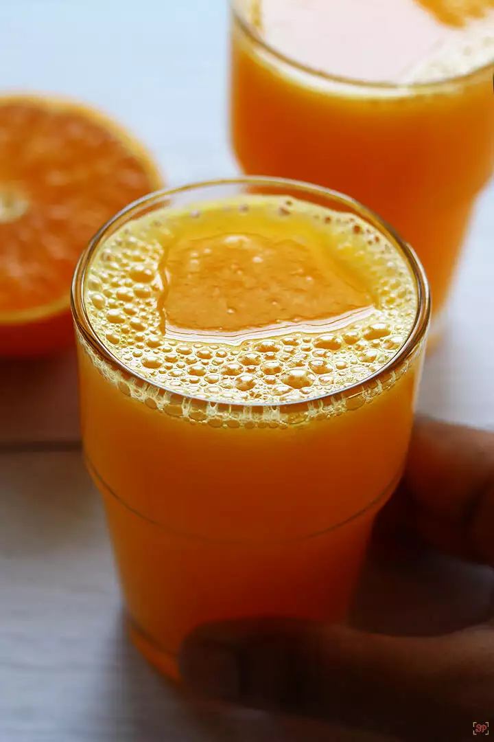 orange juice in 2 glasses with sliced orange at the side