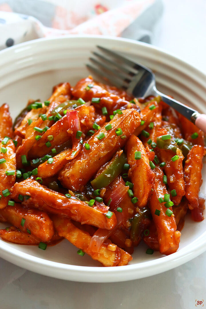 chilli potato served in a white rimmed plate