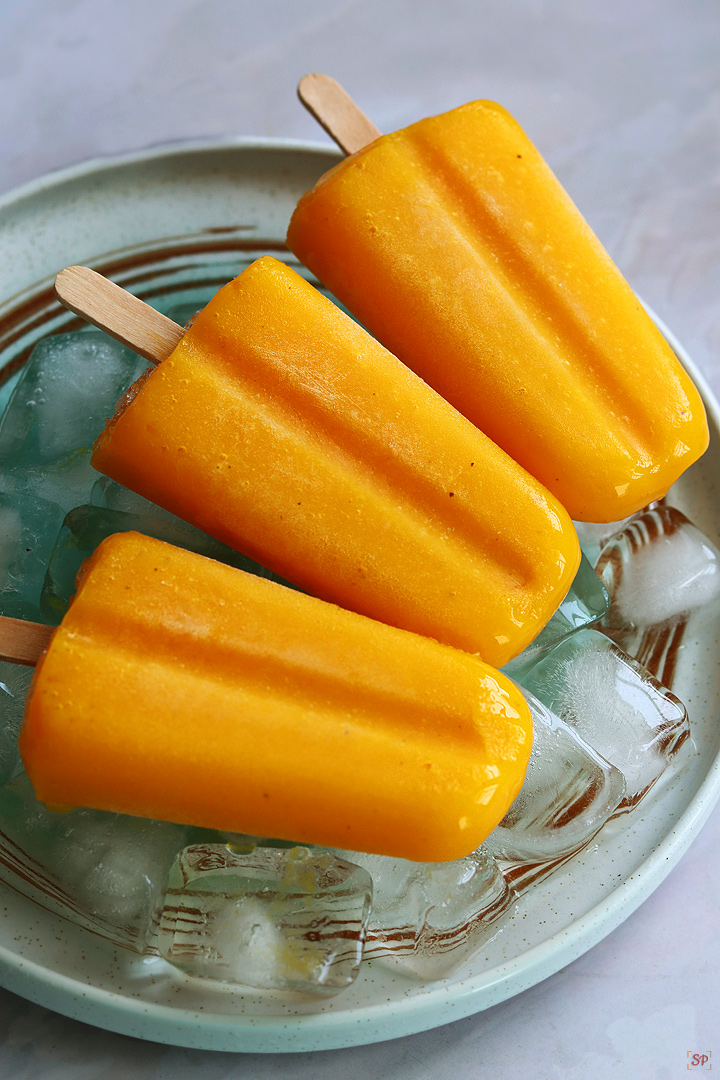 mango popsicles placed on a plate with ice cubes