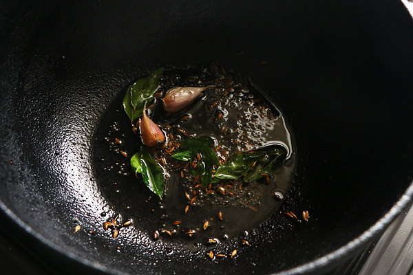 in a kadai oil is heated mustard seeds, cumin seeds are crackled then garlic, curry leaves, hing are added