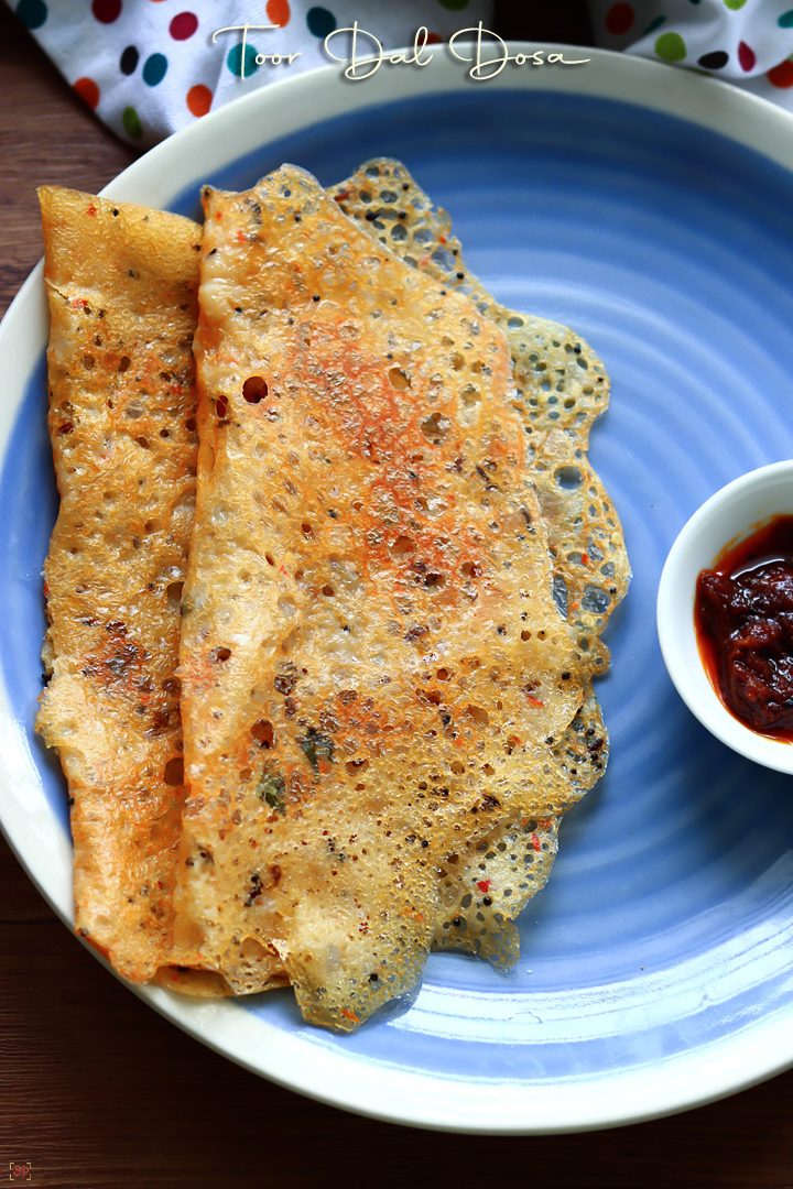 toor dal dosa placed in a blue plate with pickle on the side