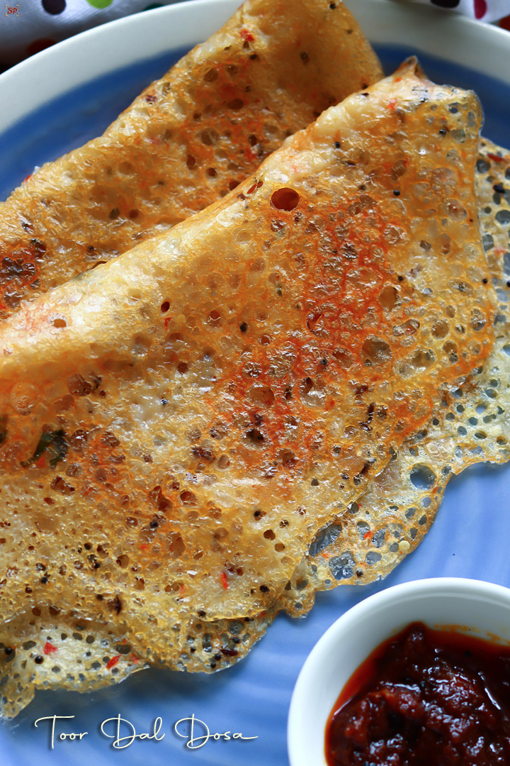 toor dal dosa placed in a blue plate with pickle on the side