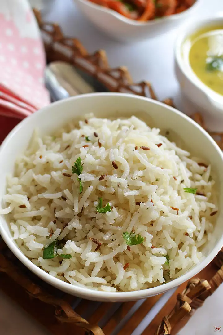 jeera rice served in a white bowl along with dal and mushroom curry