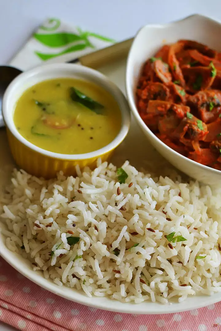 jeera rice served in a white plate along with dal and mushroom curry