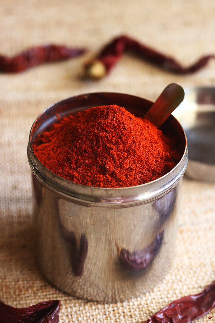 red chilli powder stored in a steel container with a spoon