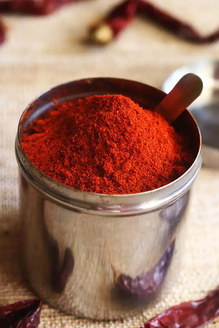 red chilli powder stored in a steel container with a spoon
