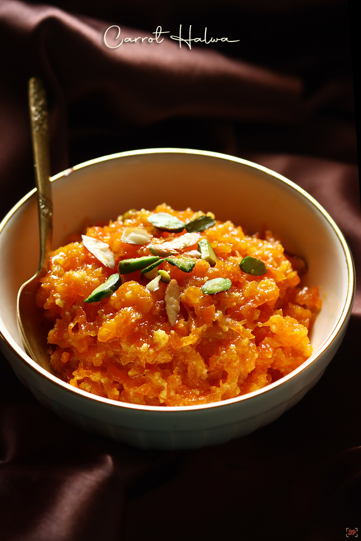 carrot halwa served in a cream bowl with golden rim with a gold spoon