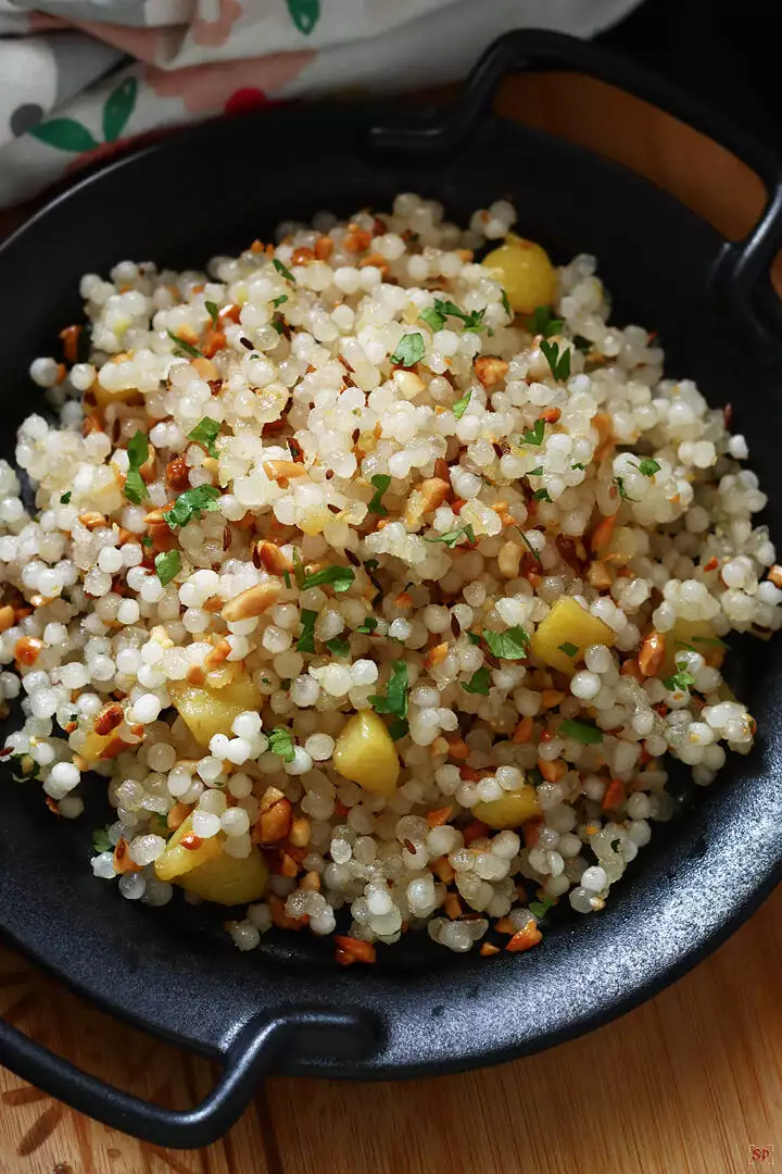 sabudana khichdi served in a black plate with handles on both the sides