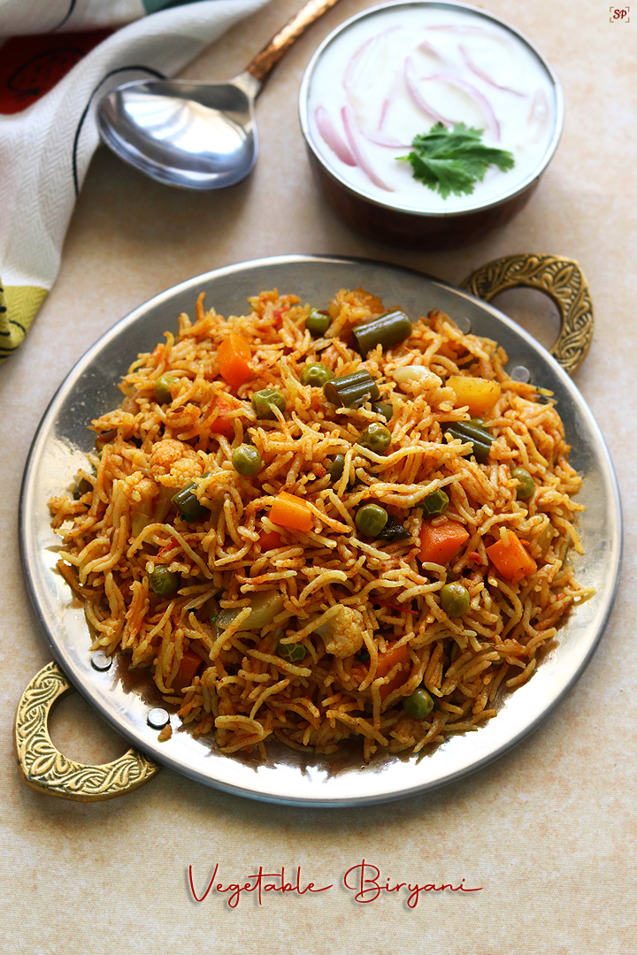 Veg Biryani served in a plate along with onion raita at the side
