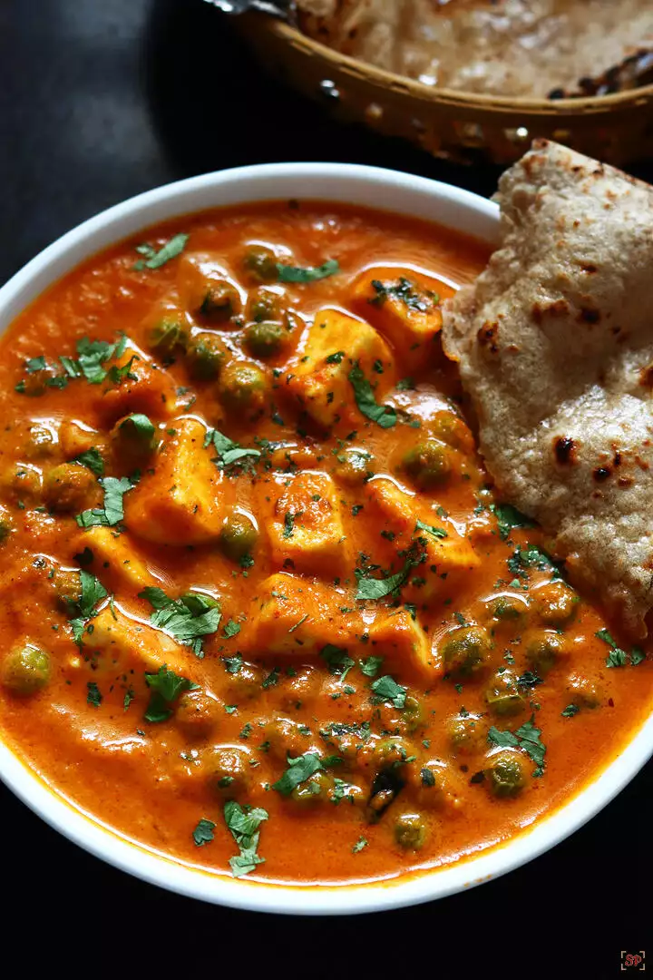 matar paneer served in a white bowl with roti