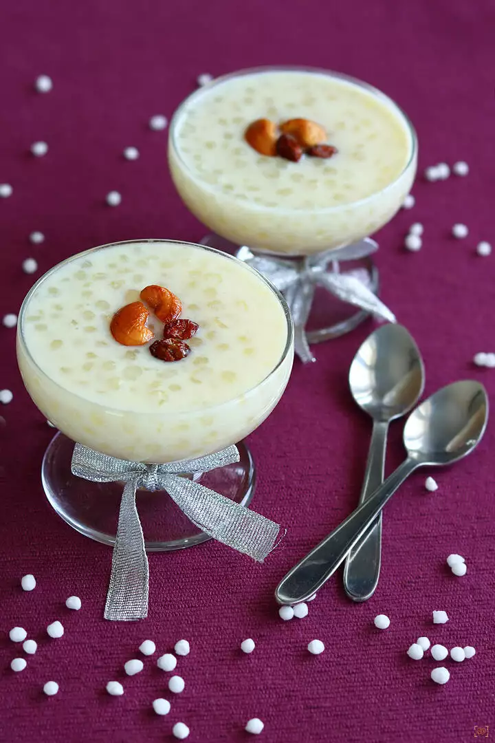 sago payasam in 2 glass bowl garnished with ghee fried cashews and nuts with spoons on the sides