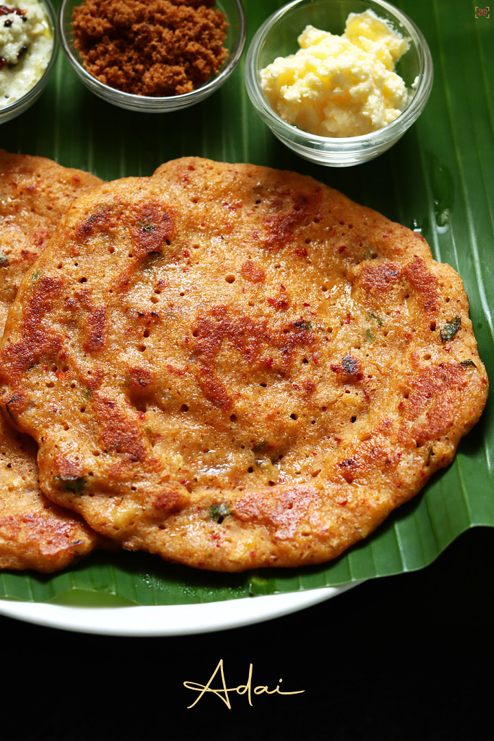 lentil crepes or adai with coconut chutney, jaggery and buter served in banana leaf