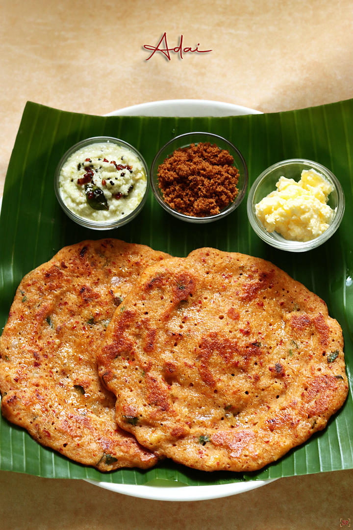 lentil crepes or adai with coconut chutney, jaggery and butter served in banana leaf